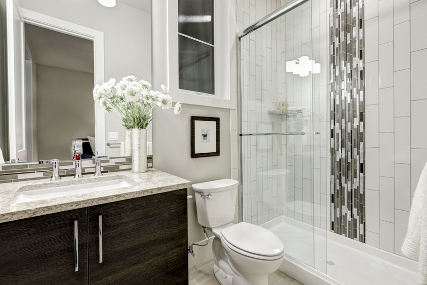 Bathroom with glass tile shower accent, toilet, vanity area, countertop, sink, cabinet, and mirror