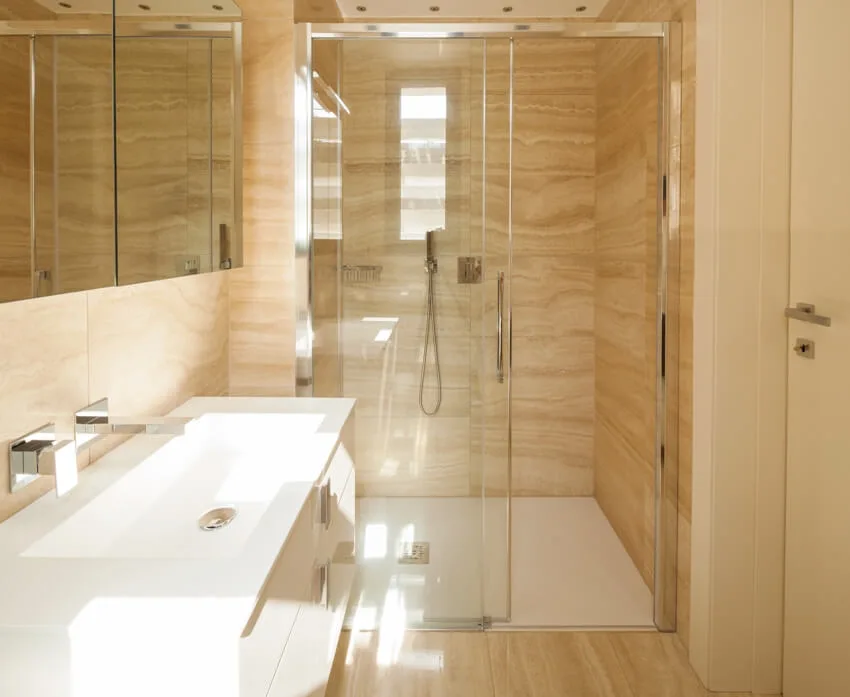 Bathroom with laminate shower walls and glass doors with white sink and mirror