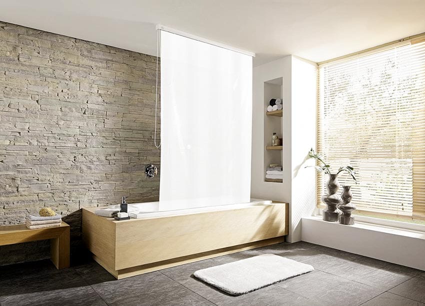 Bathroom with roller shades for shower curtains wit stone wall, tub, tile floors, and window blinds