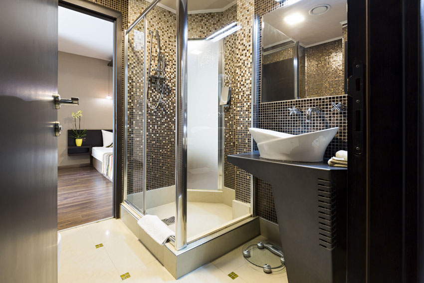Bathroom with enclosed shower, mirror and sink with view of the bedroom