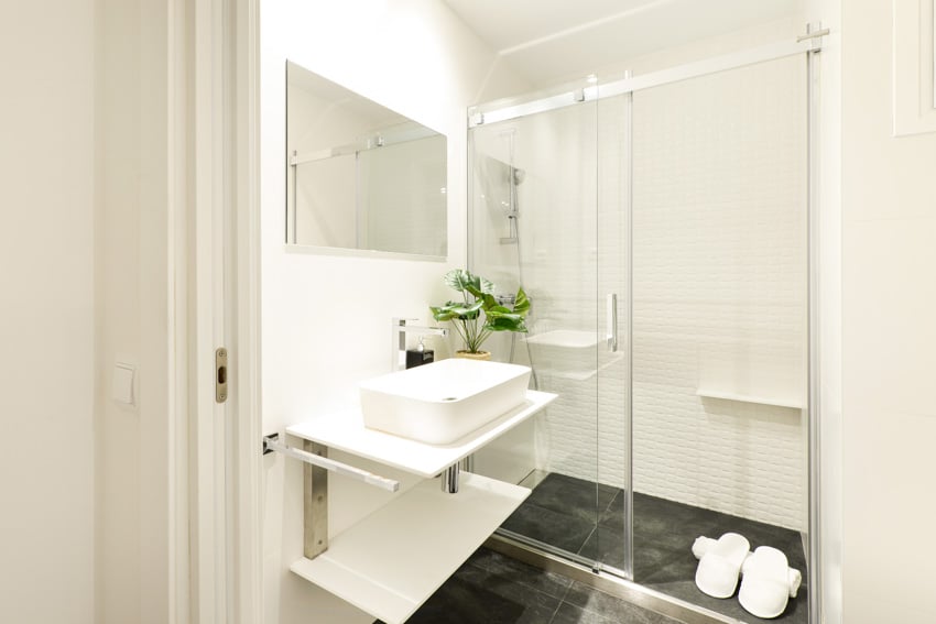 Bathroom with sliding panel door, floating countertop, sink, mirror, and tile flooring
