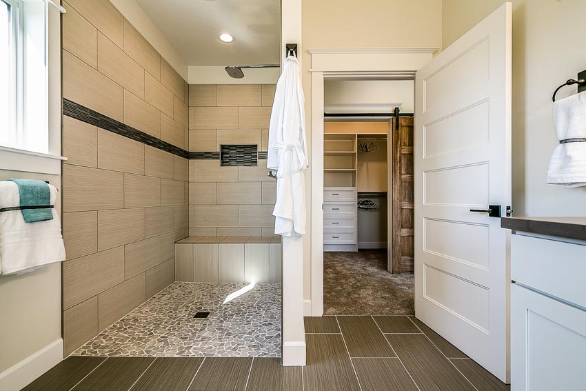 Bathroom with woodlike ceramic flooring, towel rack, door and wood cabinets