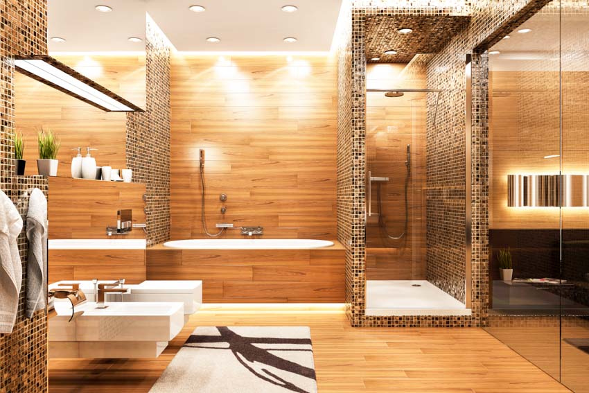 Bathroom with toilet, bidet, glass tile shower, wood accent, wall tub, and mirror