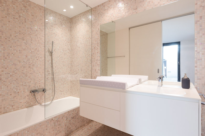 Bathroom with pink walls, mirror and solid surface countertop