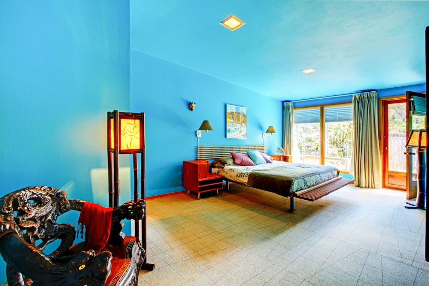 Bedroom with aqua walls, bed, nightstand, lamps, ceiling lights, window, and curtains