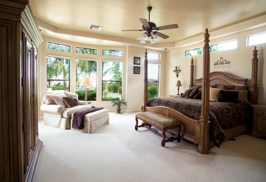 Bedroom with ceiling fan chandelier, bed, comforter, chair, pillows, and windows