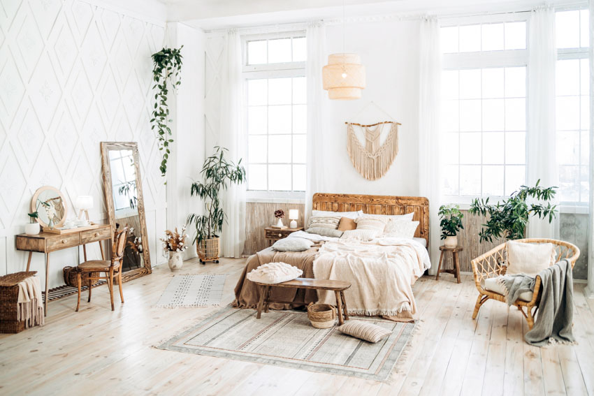 Bedroom with light brown furniture, table, chairs, mirror, wood flooring, mirror, indoor plants, windows, and curtains