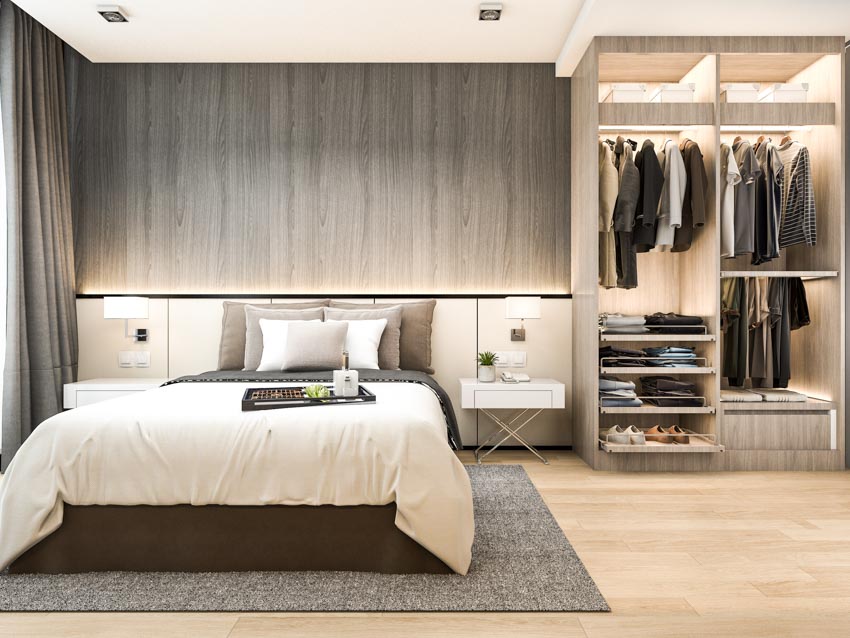 Bedroom with men's reach-in closet, nightstand, comforter, pillows, and ceiling lights