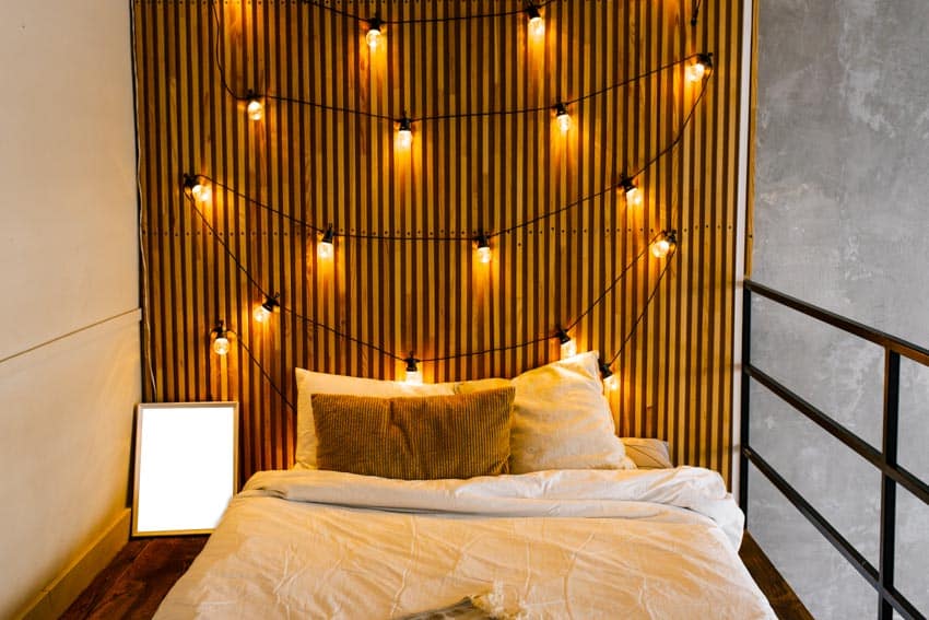 Bedroom with wood slat wall, bed, and string lights