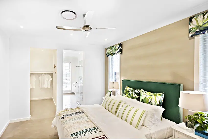 A bright and clean bedroom with cream and white walls, and comfortable bed with green and white decors
