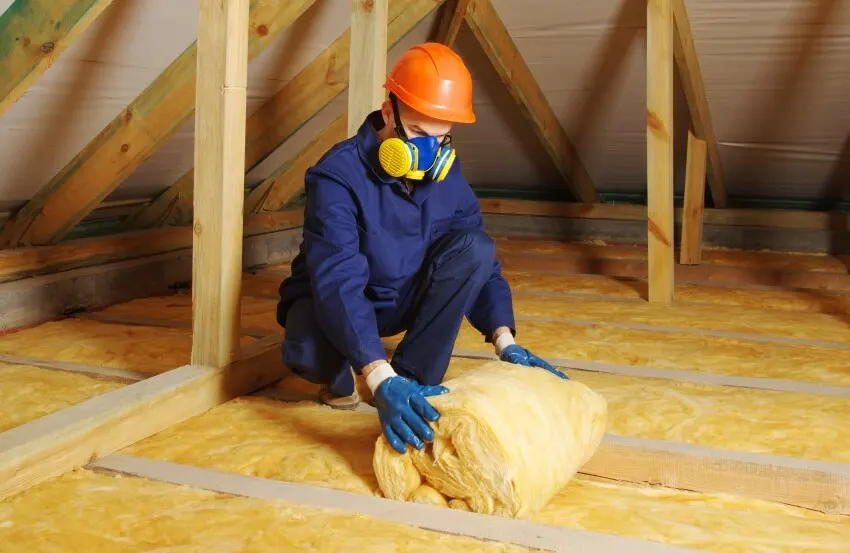 Construction worker installing fiberglass batt insulation
