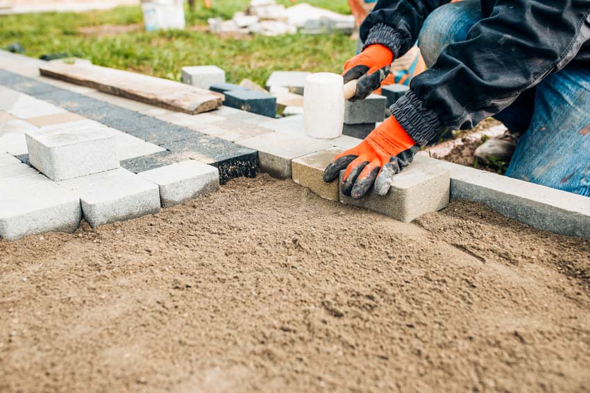 Contractor placing pavers on compacted soil