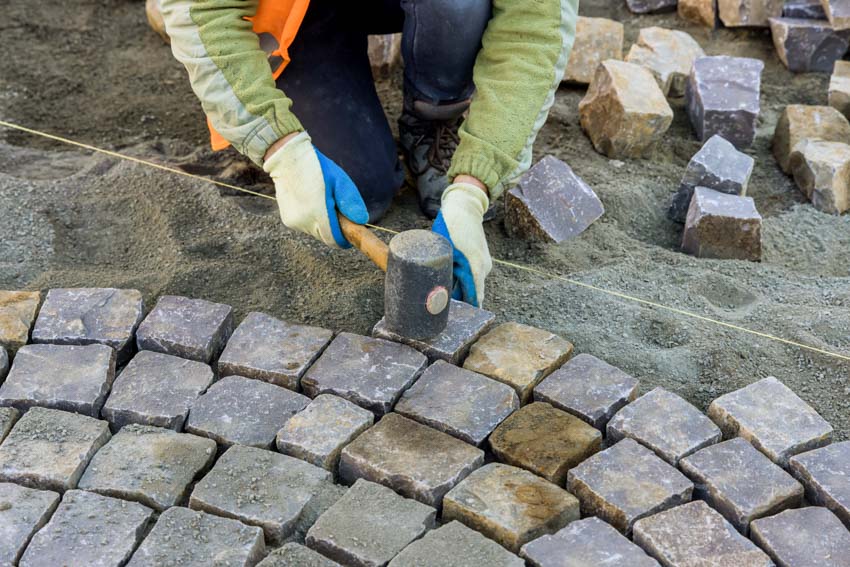 Contractor putting pavers down on stone dust
