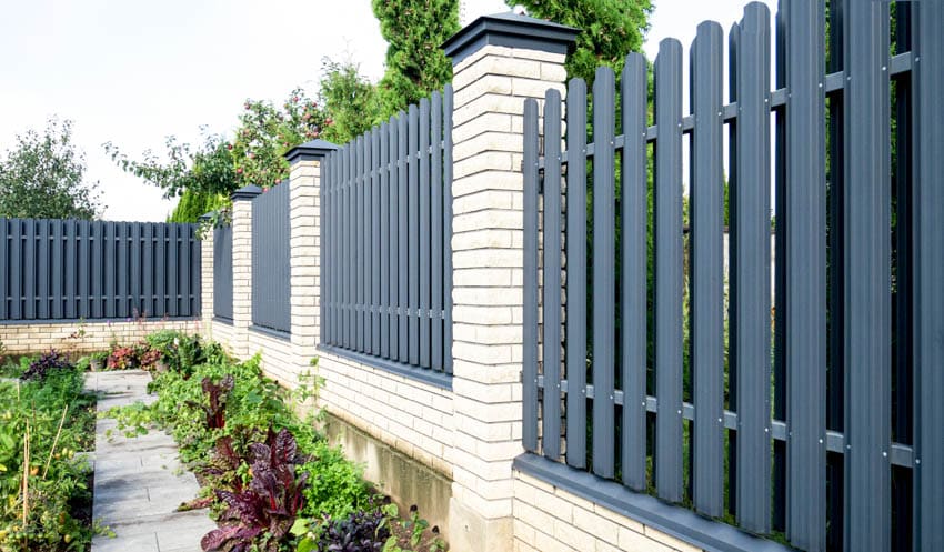 Dark gray shadow box fence with concrete foundation, pillars, and flowers
