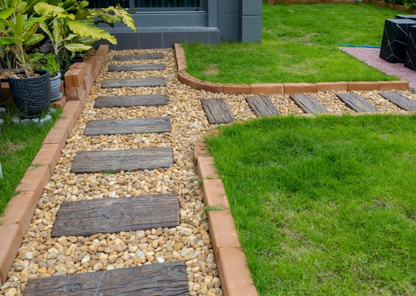 Decorative modern garden landscape with pebble stone flooring pathway and green grass on the side