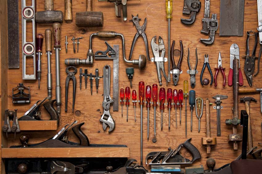 Different handyman tools organized inside a shed using a tool hanger
