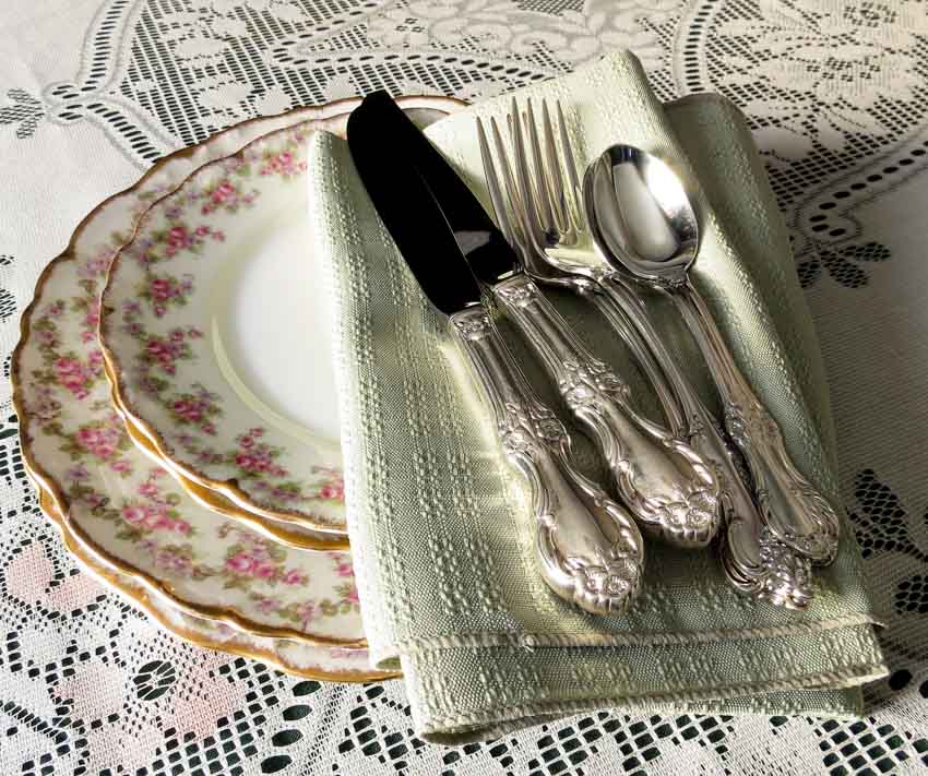 Dining table with plates, forks, spoons, European dinner knife, and a napkin