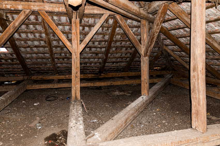 Dirty attic crawl space with wooden beam support