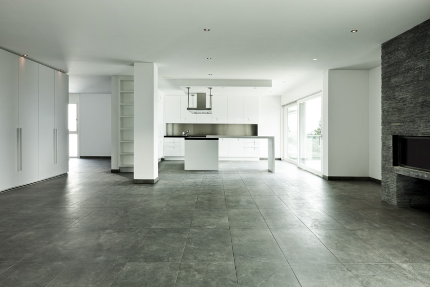 Empty kitchen with stone look porcelain tiles, island, cabinets, and glass door