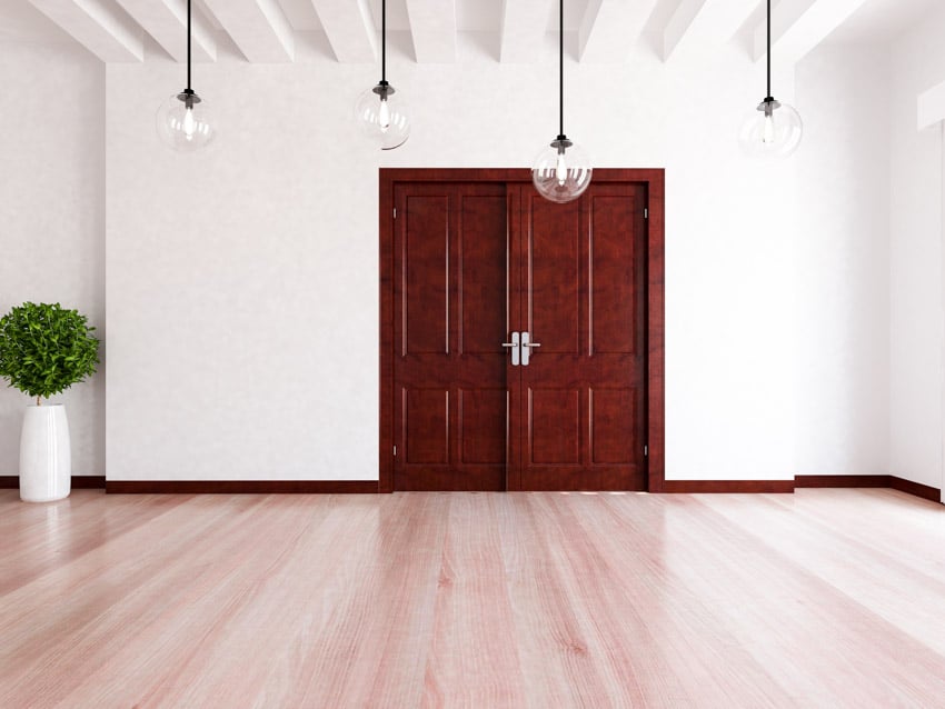 Empty room with hanging lights, wooden doors, and floors