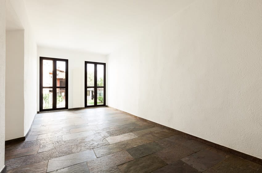 Empty room with white walls, glass doors, and stone look floor tile
