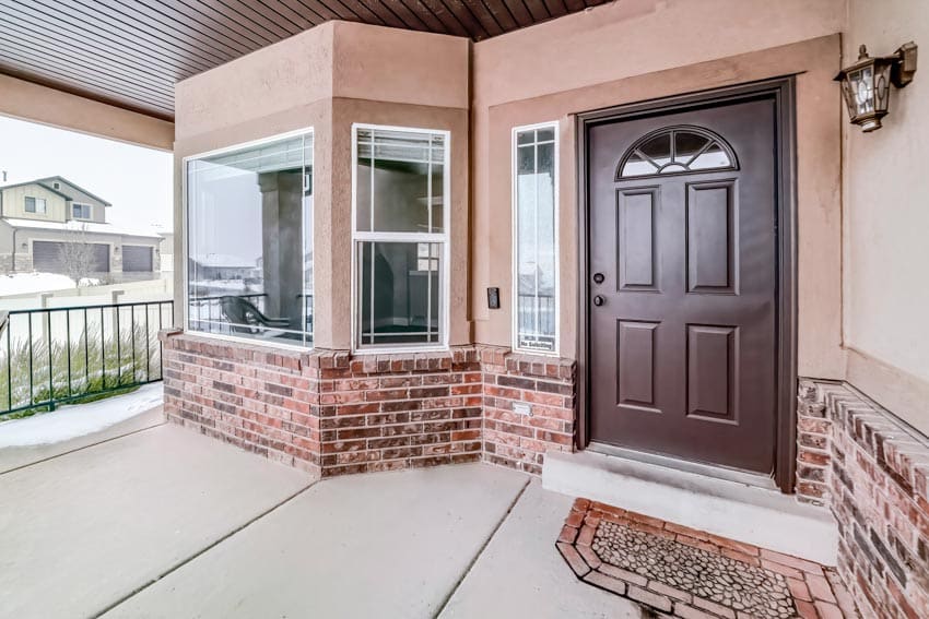 Front porch with  door with glass inserts, windows, and brick siding