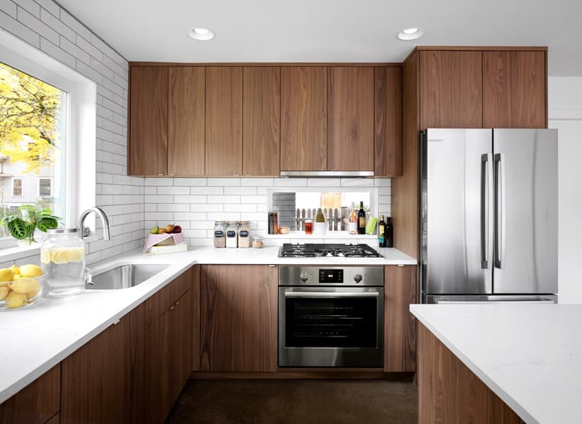 Fully fitted contemporary kitchen design with teak cabinets, quartz countertop with subway tile backsplash and stainless steel appliances