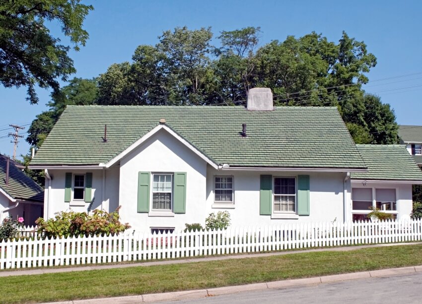 Green & white cottage house design with light green shutters and picket fence