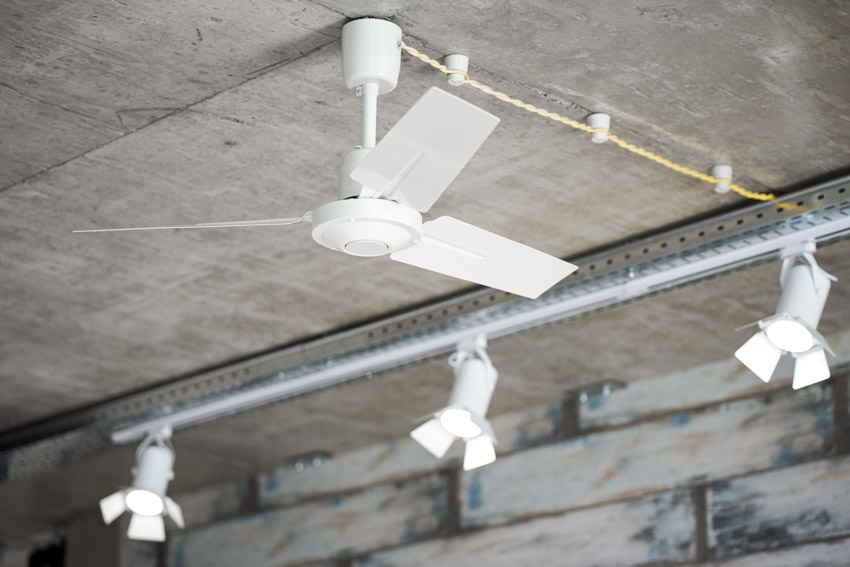 Home interior with concrete ceiling, track lighting, and white ceiling fan