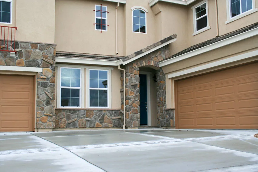 Building with fieldstone siding, windows and concrete driveway