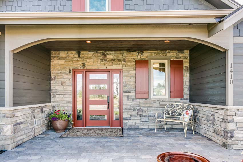Marble siding placed in the porch with red door and floor mat