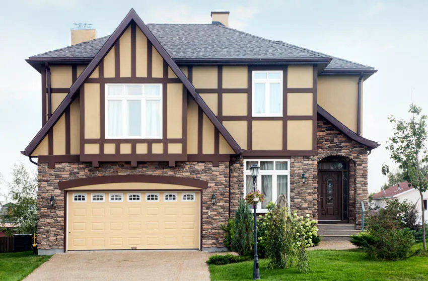 A Tudor home with wide garage doors and a front porch on the side