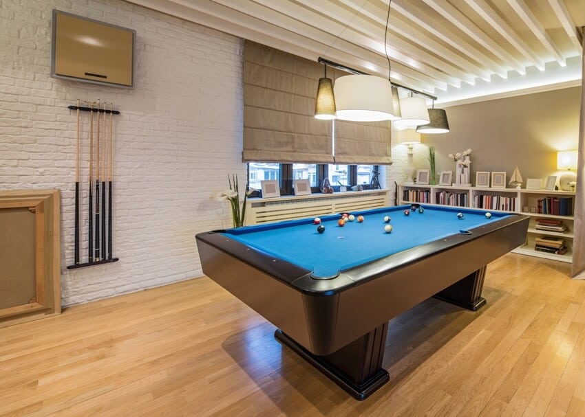 Interior of a luxury family room with floating flooring, billiard table and shelves