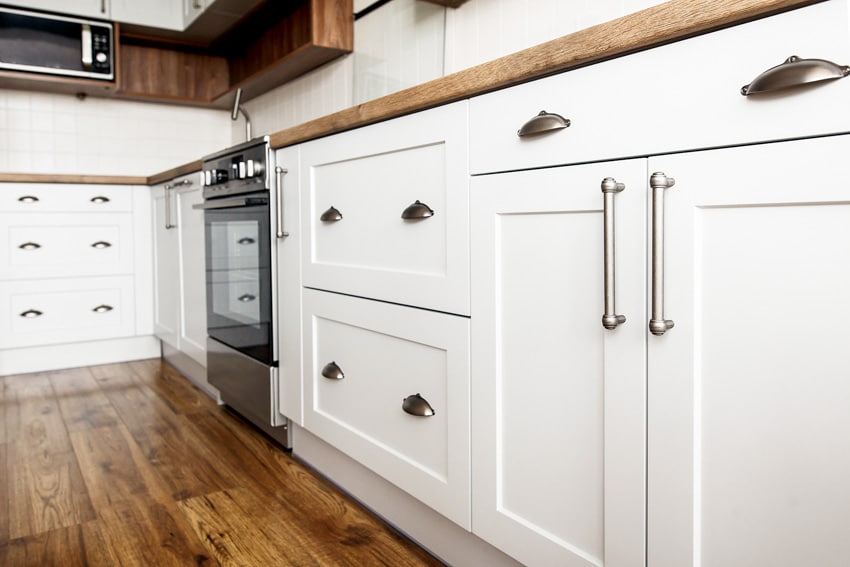 Kitchen cabinets with different hardware, wood flooring, and oven