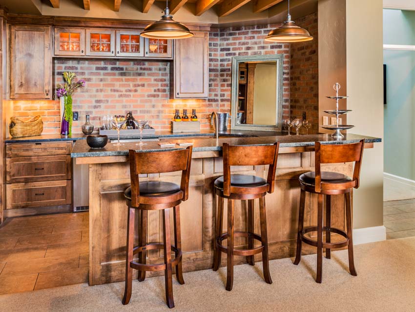 Kitchen with bar counter, high chairs, brick backsplash, pendant lights, and wood flooring
