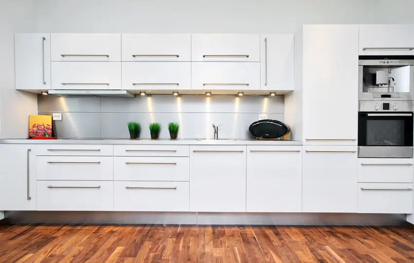 Kitchen with long hardware, white cabinets, and backsplash