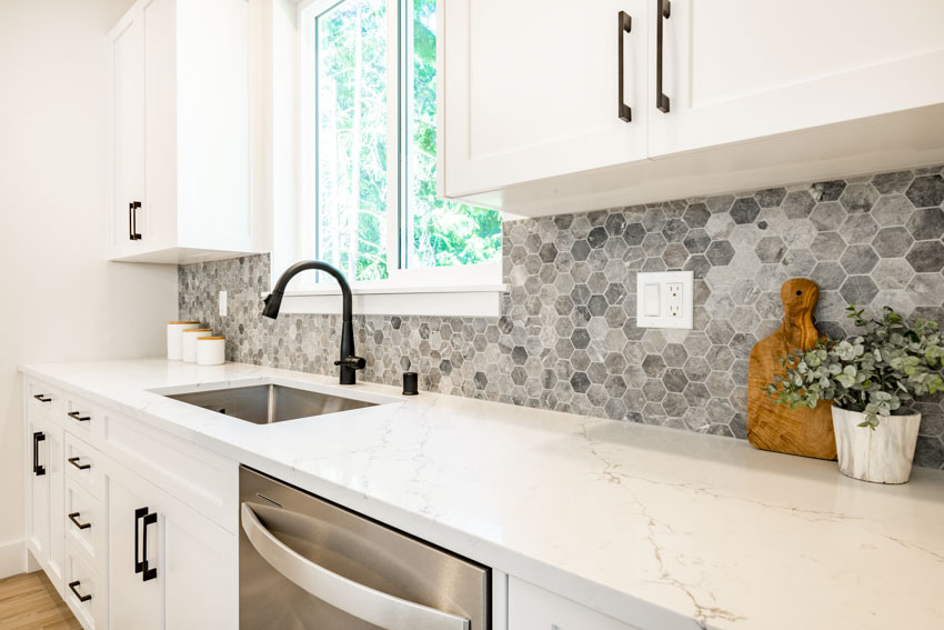 Kitchen with grey hexagonal tiles for the backsplash, Statuario marble countertop and faucet in matte black finish