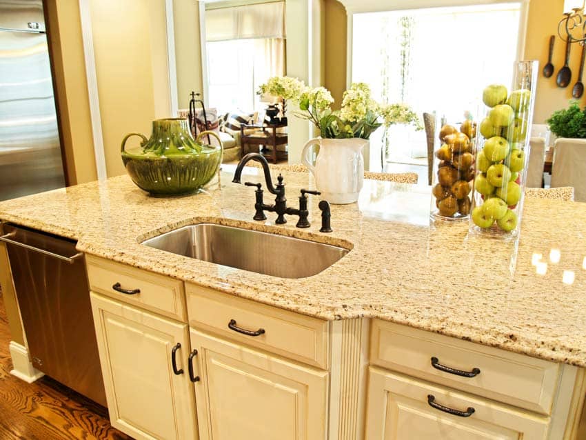 Kitchen with cabinets, drawers, ivory cream granite countertop, sink, and faucet