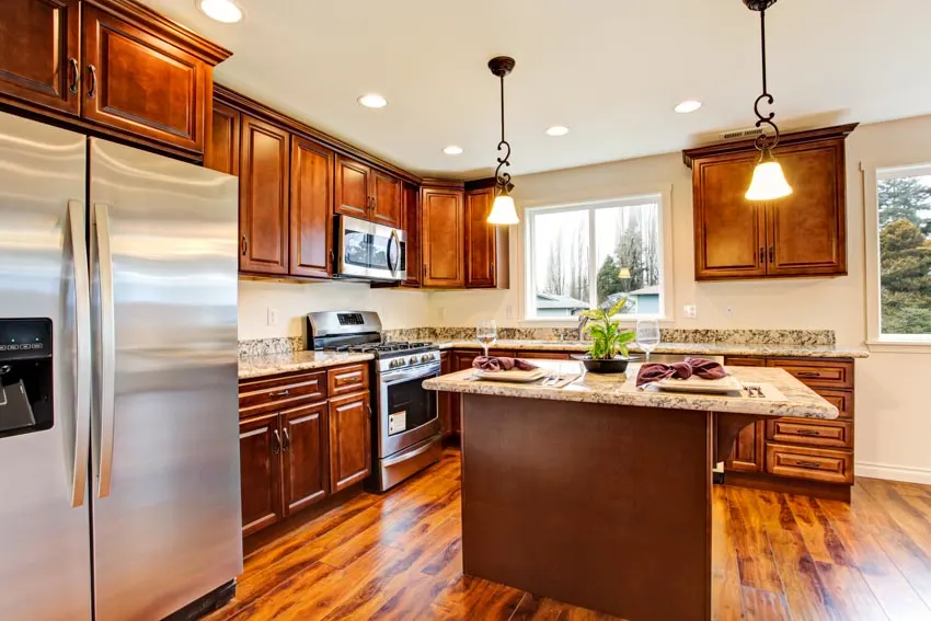 Kitchen with center island, wooden cabinets, hanging lights and granite counters