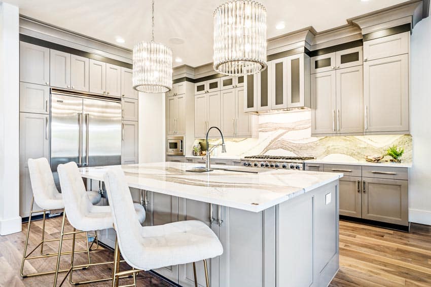 Kitchen with chandelier, countertops, chairs, island, cabinets, wood flooring, and backsplash