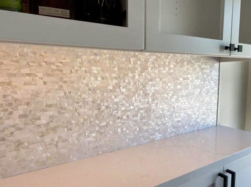 Kitchen with countertop, cabinets with black handles, and groutless backsplash