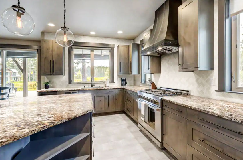 Kitchen with delicatus gold granite countertop, backsplash, cabinets, pendant lights, windows, and tile flooring