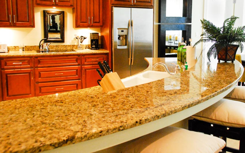 Kitchen with gold granite countertop, cabinets, backsplash, and indoor plant