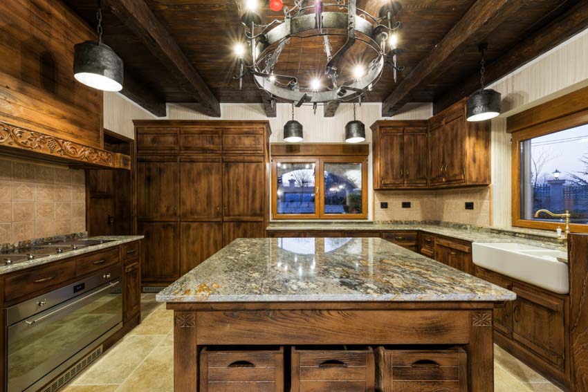 Kitchen with iron ring chandelier, island, countertops, wood cabinets, and windows