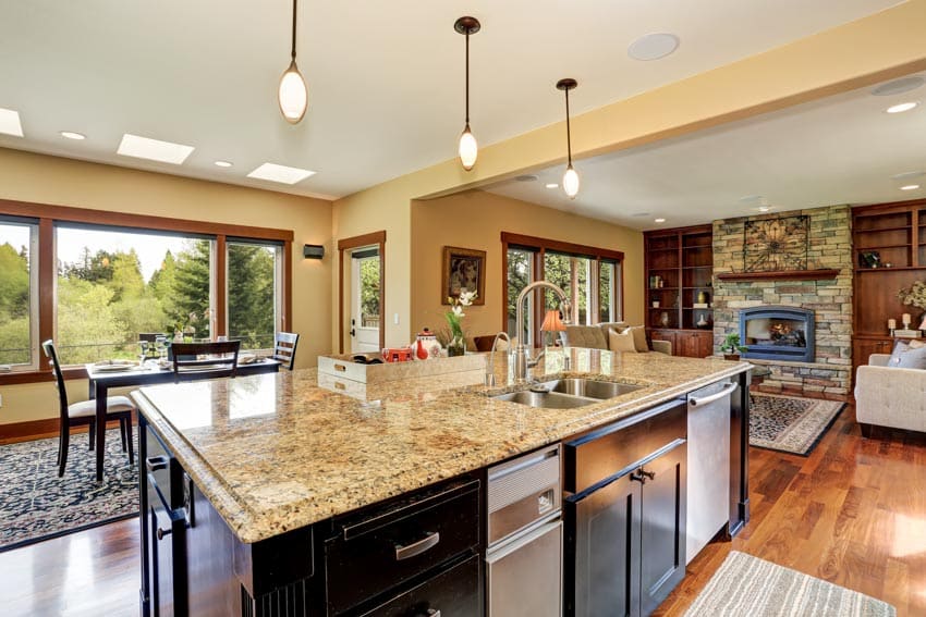 Kitchen with island, cabinets, drawers, cream granite countertop, sink, faucet, and pendant lights