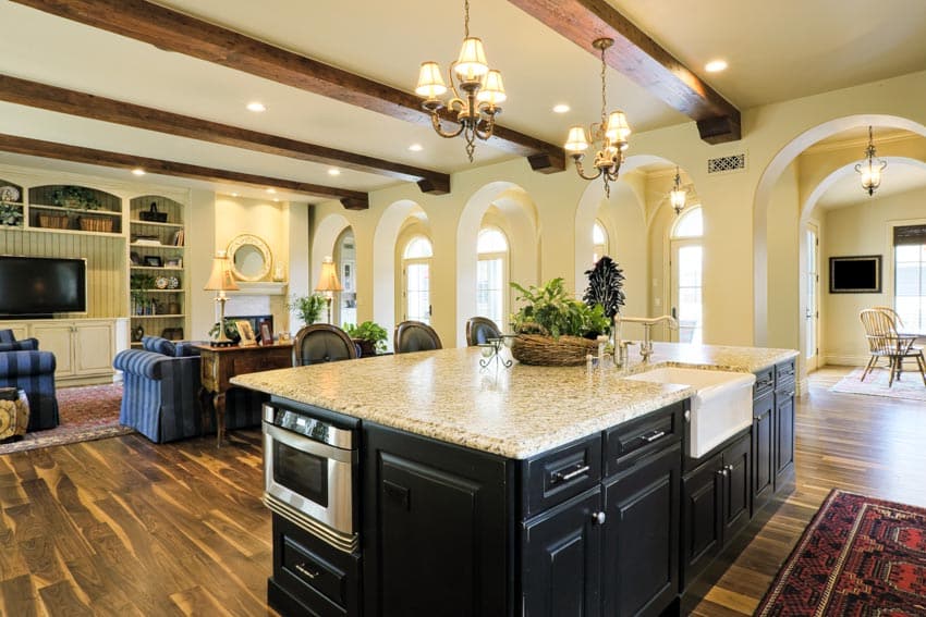 Kitchen with island, chandeliers, giallo cream granite countertop, wood flooring, ceiling beams, and cabinets