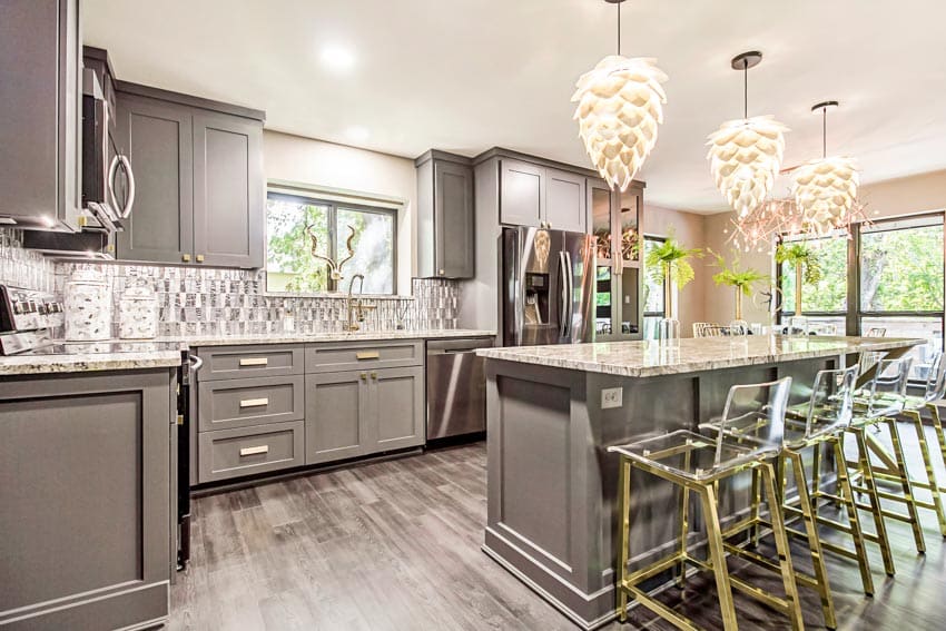 Kitchen with island, chandeliers, gray cabinets, wood floor, transparent chairs, countertops, backsplash, and windows