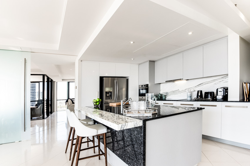 Kitchen with island, countertops, chairs, cabinets, ceiling lights, and stone backsplash