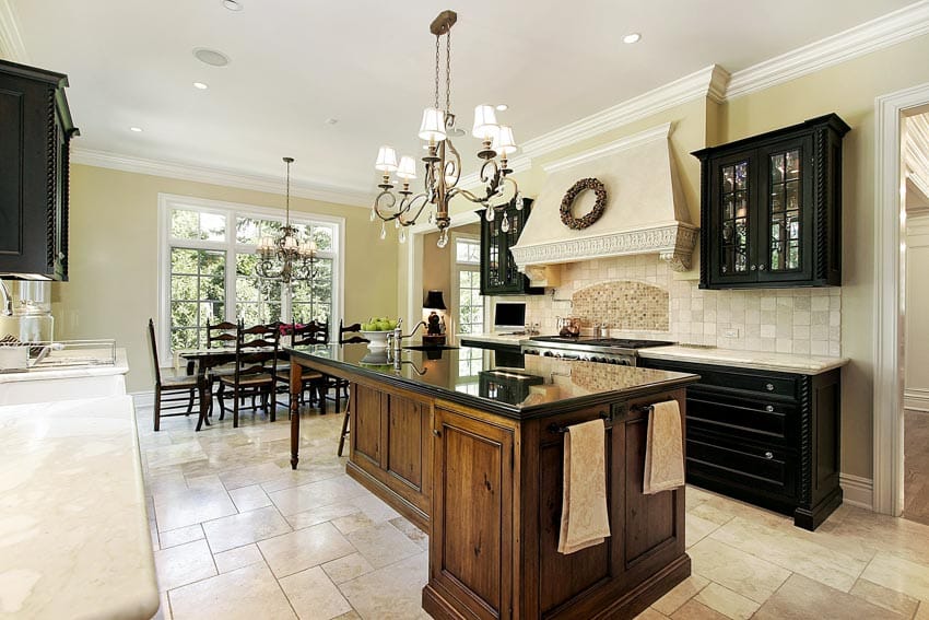 Kitchen with island, countertops, chandelier, cabinets, tile flooring, and range hood