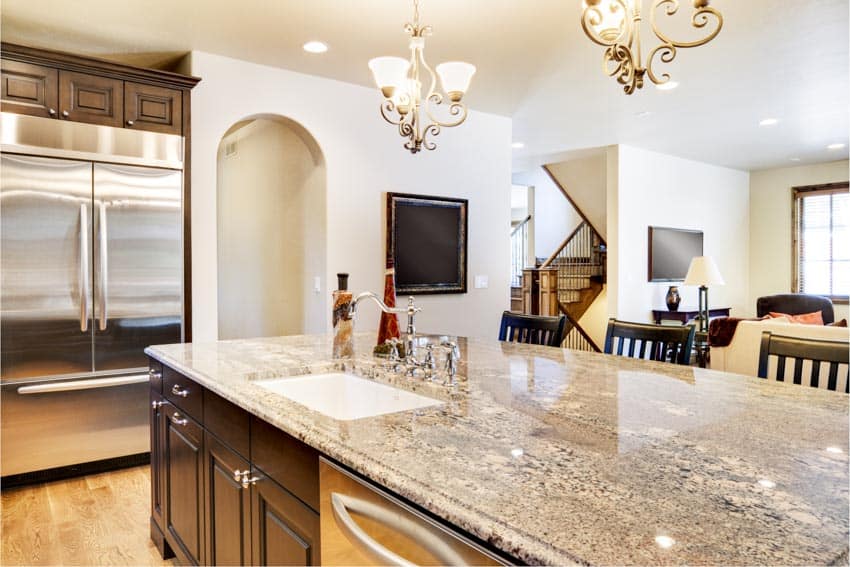 Kitchen with island kashmir cream granite countertop, sink, refrigerator, and chandeliers